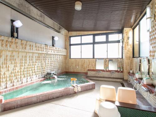 a large bathroom with a hot tub with chairs in it at Aqua Garden Hotel Fukumaru in Kagoshima