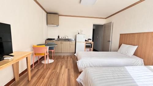 a small room with two beds and a kitchen at Garden in Jeju 201 in Seogwipo