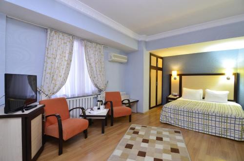 a hotel room with a bed and chairs and a television at Grand Gebze Hotel in Gebze