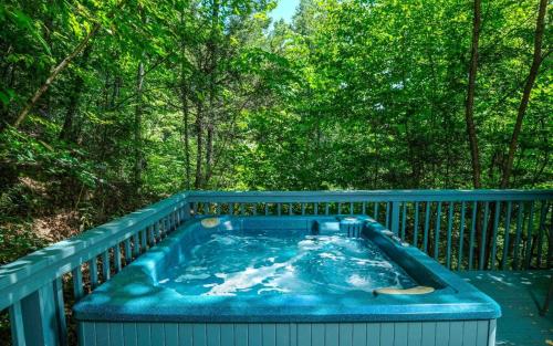 a blue hot tub on a deck with trees at Ski Mountain Hideaway 1154 in Gatlinburg