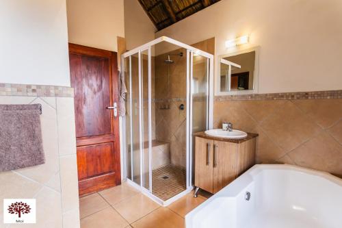 a bathroom with a tub and a shower and a sink at Zebula Golf and Wildlife Estate - Spectacular View Pax 13 - Moi Signature Luxury villa in Mabula