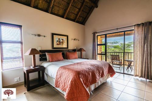 a bedroom with a bed and a balcony at Zebula Golf and Wildlife Estate - Spectacular View Pax 13 - Moi Signature Luxury villa in Mabula