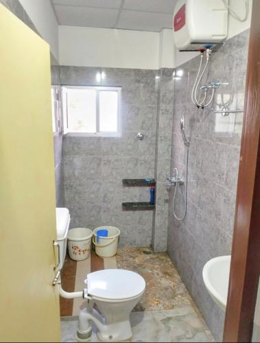 a bathroom with a shower and a toilet and a sink at Yangzom Homez in Siliguri