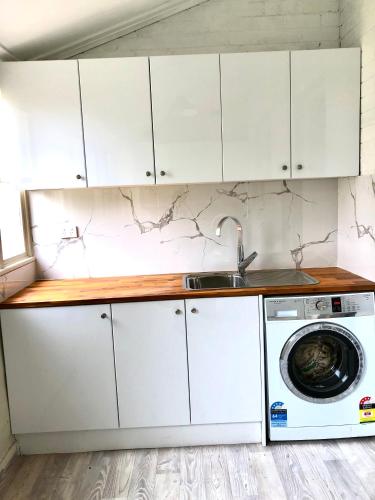 a kitchen with white cabinets and a washing machine at Spacious private room minutes away from Eastwood in Sydney