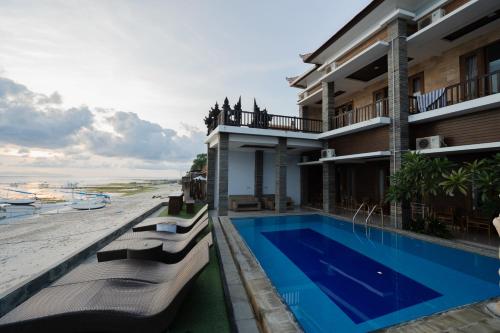 a building with a swimming pool next to a beach at Barton Beach Inn in Nusa Penida