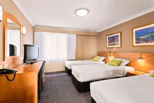 a hotel room with two beds and a television at Quality Inn Penrith Sydney in Penrith