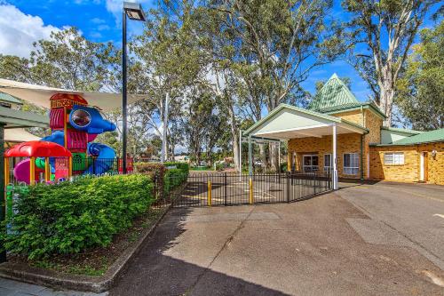 a house with a playground in front of a building at Quality Inn Penrith Sydney in Penrith