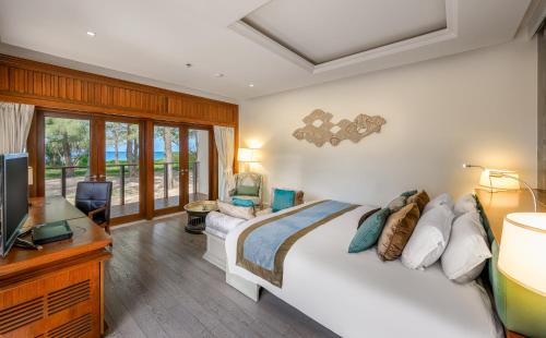 ein Schlafzimmer mit einem Bett, einem Schreibtisch und einem Fernseher in der Unterkunft Maikhao Dream Villa Resort and Spa, Maikhao Phuket in Mai Khao Beach