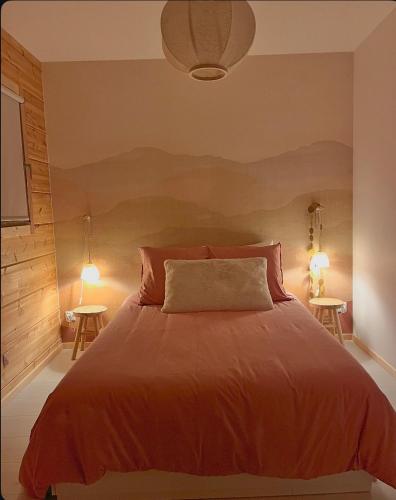 - une chambre avec un lit avec des draps orange et 2 tables dans l'établissement Le Cottage des Cerisiers, à Saint-Paul-en-Cornillon