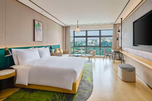 a hotel room with a large bed and a flat screen tv at Hilton Garden Inn Foshan Lishui-Free Shuttle Bus for Canton Fair in Foshan