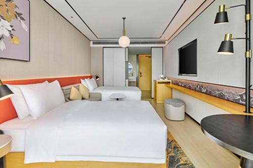 a hotel room with a large white bed and a tv at Hilton Garden Inn Foshan Lishui-Free Shuttle Bus for Canton Fair in Foshan