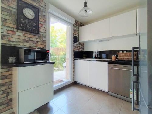 une cuisine avec des placards blancs et une horloge murale dans l'établissement Chic apart with piano, terrace and parking, à Saint-Denis