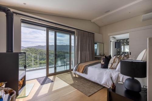 a bedroom with a bed and a large window at Tren Villa in Plettenberg Bay