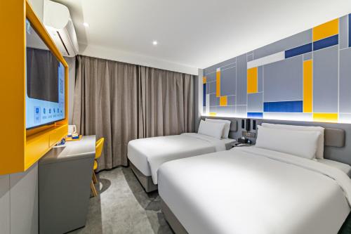 a hotel room with two beds and a tv at 7Days Inn Xi'an East Street in Xi'an