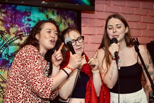 a group of three women singing into microphones at Mild Life Hostel Rishikesh in Rishīkesh
