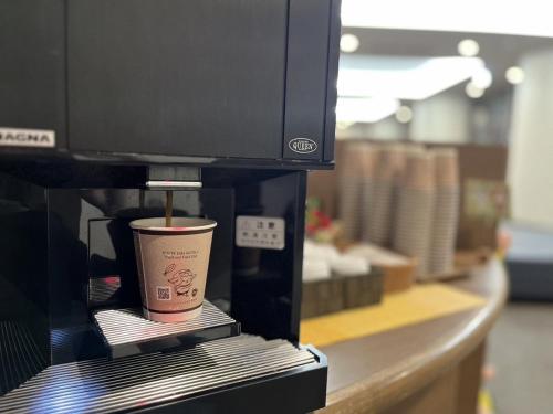 a cup of coffee in a coffee maker at Hotel Route Inn Grand Asahikawa Ekimae in Asahikawa