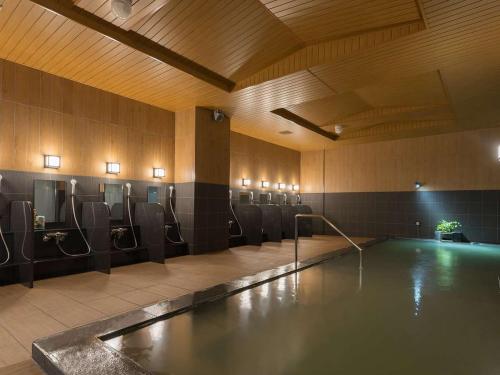 a swimming pool in a bathroom with chairs and a swimming pooliterator at Hotel Route Inn Grand Asahikawa Ekimae in Asahikawa