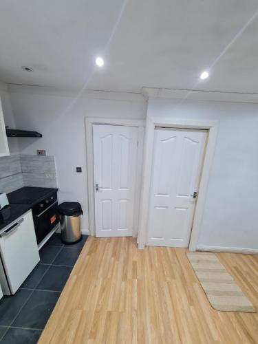 a kitchen with two white doors and a wooden floor at Garden house in Tilbury