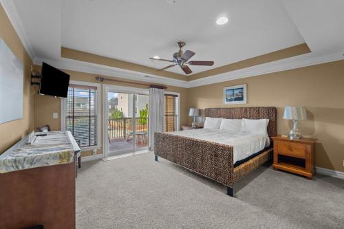 a bedroom with a bed and a television and a balcony at Croatan Surf Club by KEES Vacations in Kill Devil Hills