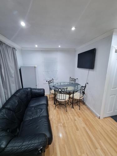 a living room with a black leather couch and a table at Garden house in Tilbury