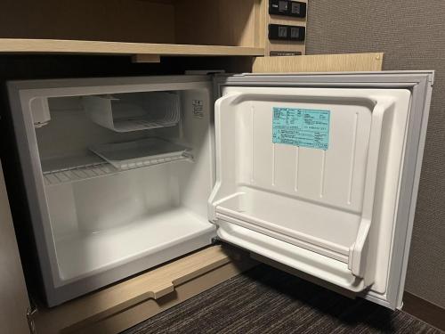an empty refrigerator with its door open in a kitchen at Hotel Route Inn Grand Asahikawa Ekimae in Asahikawa