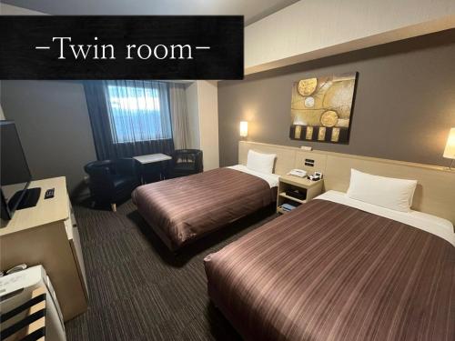 a hotel room with two beds and a tv at Hotel Route Inn Grand Asahikawa Ekimae in Asahikawa