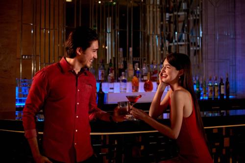 a man and a woman standing at a bar holding a drink at Courtyard by Marriott Bandung Dago in Bandung