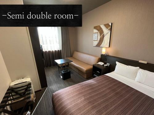 a hotel room with a bed and a couch at Hotel Route Inn Grand Asahikawa Ekimae in Asahikawa