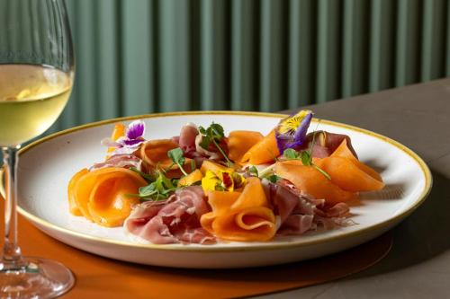 a plate of food on a table with a glass of wine at Courtyard by Marriott Milano Linate in Milan