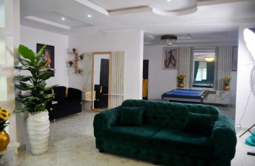 a living room with a green couch and a piano at White House Villa Ogombo in Sangotedo
