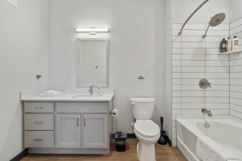 a bathroom with a toilet and a sink and a tub at CozySuites Mass w parking lounge & roof deck #26 in Indianapolis