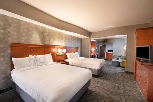 a hotel room with two beds and a television at Courtyard Atlanta McDonough in McDonough