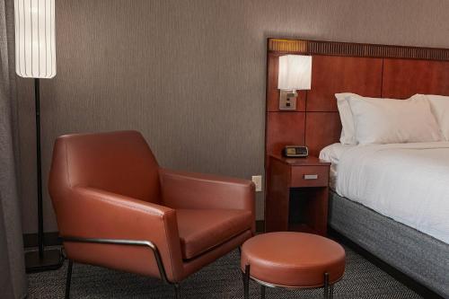 a hotel room with a chair and a bed at Courtyard Medford Airport in Medford