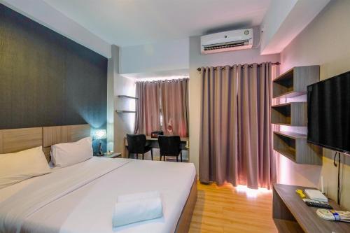 une chambre d'hôtel avec un lit et un bureau avec une table dans l'établissement Cozy Living and Homey Studio Apartment at Margonda Residence 5 By Travelio, à Depok