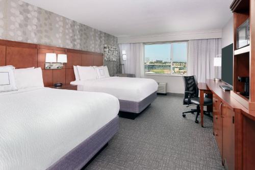 a hotel room with two beds and a desk at Courtyard Fort Wayne Downtown at Grand Wayne Convention Center in Fort Wayne