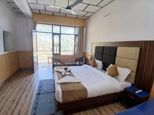 a bedroom with a large bed and a large window at Hotel Cloud Height in Dharmsala