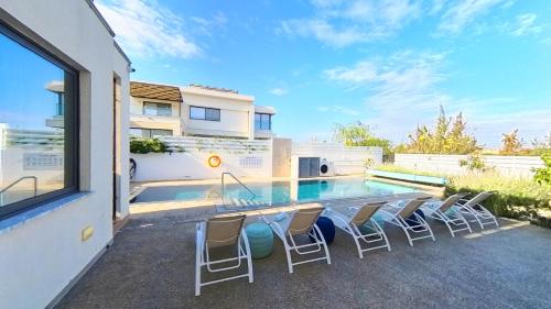 a patio with chairs and a swimming pool at Billy's Place Protaras Luxury Villa with private pool with heated pool option for autumn and winter months in Paralimni