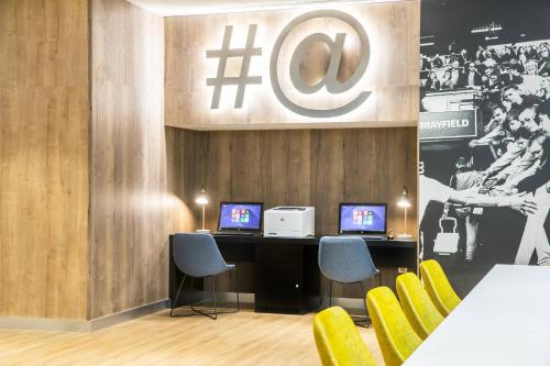 a room with two computers on a desk with yellow chairs at Courtyard by Marriott Edinburgh West in Edinburgh