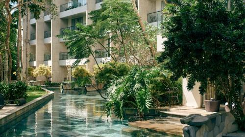 a hotel courtyard with a pool in front of a building at RIMBA by AYANA Bali in Jimbaran