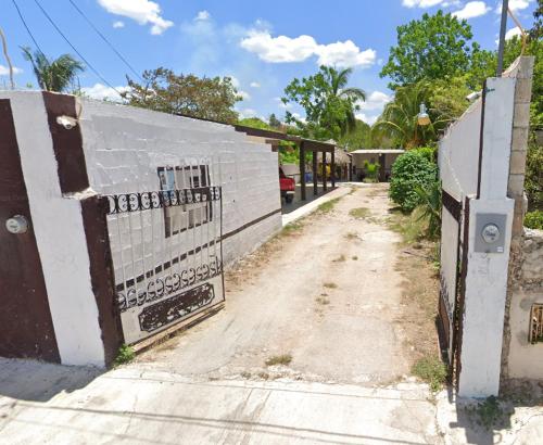 a dirt road with a fence and a building at Casa de reyes in Tizimín