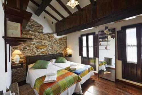 a bedroom with two beds and a stone wall at Casa La Palomba in Cudillero