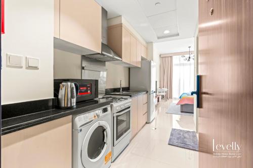 a kitchen with a washing machine and a washer at Luxury Studio in DAMAC Hills with Premium Amenities in Dubai