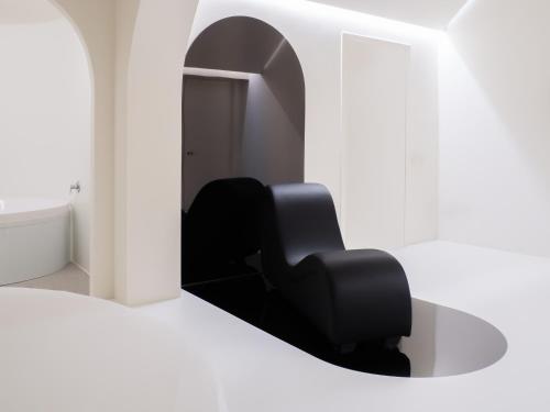 a black chair in a white room with a mirror at Dealuna Motel in Fidenza