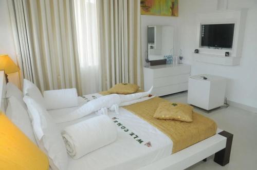 a white bedroom with two beds and a television at Amara White Villa in Ahungalla