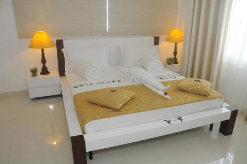 a bedroom with a white bed with two lamps at Amara White Villa in Ahungalla