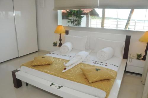a bedroom with a large bed with white sheets and pillows at Amara White Villa in Ahungalla