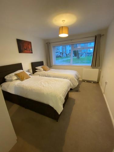 two beds in a room with a window at 2-Bed Sleeps 4 Comfy For Contractors With Free Parking in Crawley near Gatwick Manor Royal Refurbished in Crawley