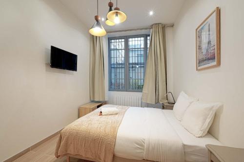 une chambre avec un grand lit blanc et une fenêtre dans l'établissement Bel Appartement Buttes-chaumont, à Paris