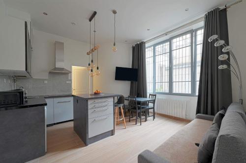 une cuisine et un salon avec un canapé et une table dans l'établissement Bel Appartement Buttes-chaumont, à Paris