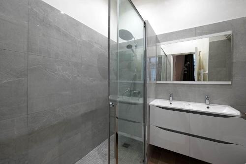 une salle de bain avec un lavabo et une douche en verre dans l'établissement Bel Appartement Buttes-chaumont, à Paris